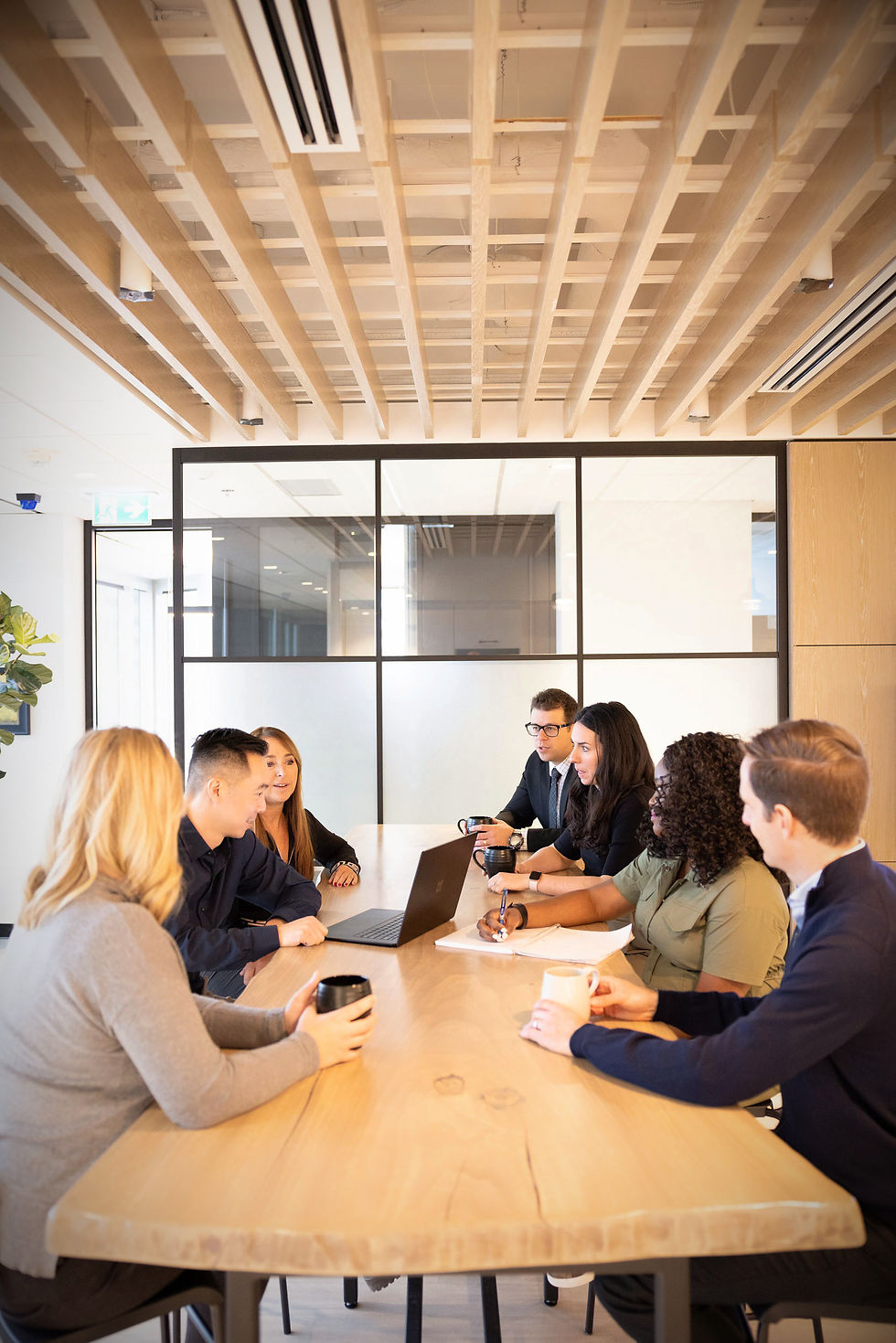 employess that are part of the coril holdings team, sitting in the boardroom with a live edge table