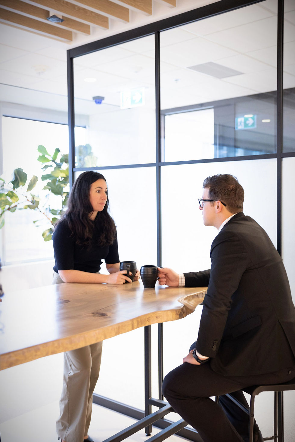 male and female coril holdings employees having coffee at a high top live-edge table