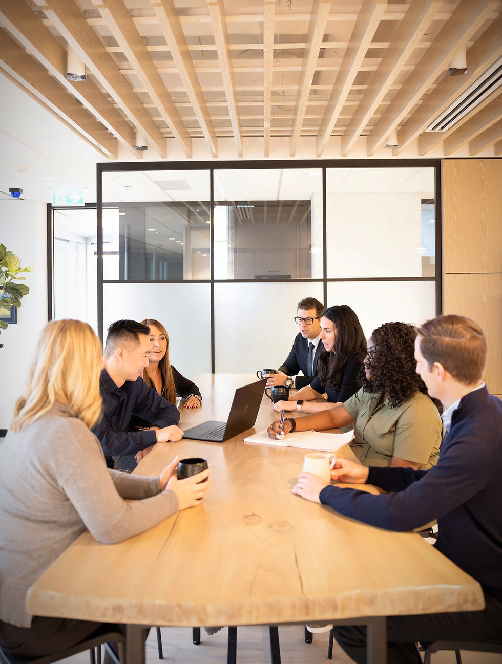 coril holdings employees having a meeting around a live-edge wood table