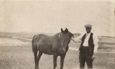 Man stands with a horse in a field; vintage photo. mannix family calgary.