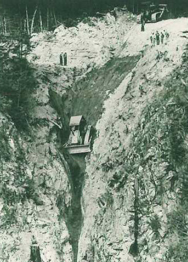 A deep trench with machinery and workers, digging for something unknown.