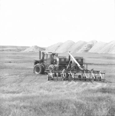 Large tractor seeding a field on a prairie landscape, agricultural farming.